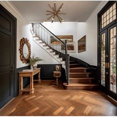 a foyer with wooden floors and black painted walls, stairs leading up to the second floor