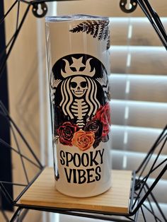 a starbucks cup sitting on top of a wooden shelf next to a window with the words spooky vibes printed on it