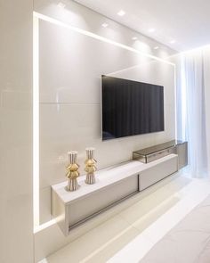 a flat screen tv mounted to the side of a wall in a white living room