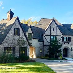 a large brick house with lots of windows on the front and side of it, surrounded by lush green grass