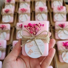 a hand holding a soap with pink flowers on it in front of some small boxes