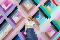 a woman standing in front of a colorful wall