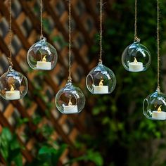 some glass balls with candles inside them hanging from chains