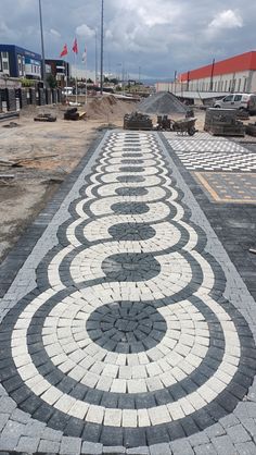 a brick walkway with white and black designs on it in front of a building under construction