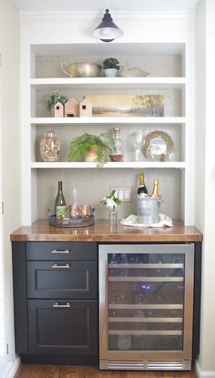 a kitchen with open shelving and wine bottles on the top shelf in front of it