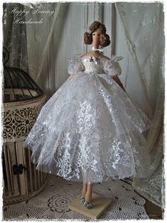 a doll dressed in white is standing on a table next to a birdcage