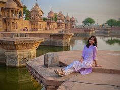 a woman sitting on top of a cement platform next to water