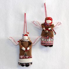 two ornaments hanging from strings in the shape of angel and snowman on white background