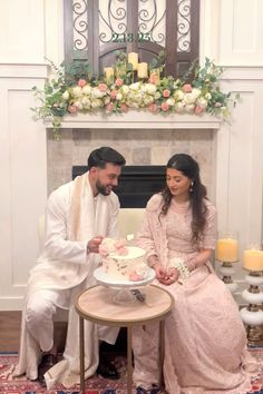 a man and woman sitting in front of a cake