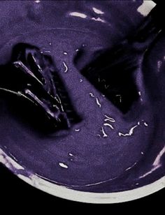 a purple substance is in a white bowl with a black object on it's side