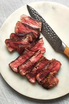 sliced steak on a plate with a knife next to it