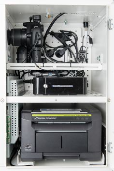 the inside of a white cabinet with electronics and equipment in it's shelves,