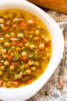 a white bowl filled with chickpeas and carrots next to a loaf of bread