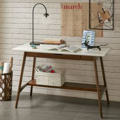 a desk with books and magazines on it in front of a white brick wall that reads march