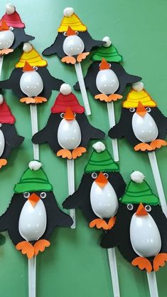 there are many penguin cupcakes with hats on them and candy sticks in the shape of penguins