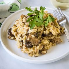 a white plate topped with rice covered in mushrooms and parsley next to a glass of milk