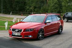 a red volvo wagon is parked on the side of the road with another car behind it