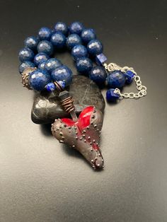 "OOAK artisan made armored glass heart pendant with huge faceted lapis round gemstones hand knotted necklace.  This necklace will adjust from 17\" to 20\" and anywhere in between.  The heart pendant hangs down an additional 2 1/2\". So, what can I say about this incredible necklace with an amazing piece of artwork heart pendant?!  Yes, it's true that I LOVE pieces that don't look like everything else out there.  So when I first saw this unbelievable lampwork heart with what looks like armor attached to it I was instantly in love because there have been many times in my own life when I could have used a cloak of armor around my own heart. 😢   I decided to use this incredible pendant with all gorgeous blue lapis hand knotted with sturdy knotting cord.  There is also one armored lampwork lar Artisan Necklace With Adjustable Heart Beads, Artisan Jewelry With Faceted Beads As A Gift, Artisan Jewelry With Faceted Beads For Gifts, Artisan Necklace With Heart Beads For Gift, Artisan Heart Necklace With Natural Stones, Unique Heart-shaped Necklaces With Natural Stones, Unique Lapis Lazuli Necklace For Gift, Unique Blue Jewelry For Valentine's Day, Fusion Style Faceted Bead Necklaces As Gift