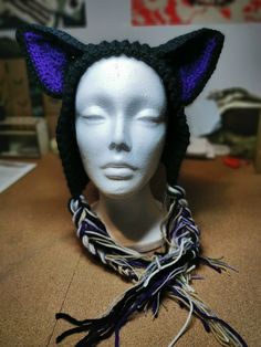 a white mannequin head wearing a black and purple knitted cat ear hat