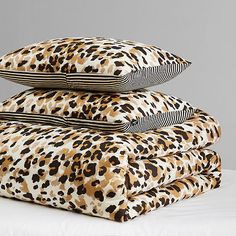 three pillows stacked on top of each other in different colors and patterns, one is leopard print