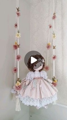 a teddy bear is sitting on a swing with flowers hanging from it's sides