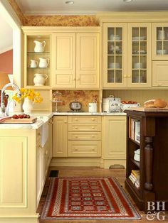 a kitchen with yellow cabinets and an area rug