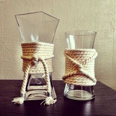 two glass vases sitting on top of a table next to rope wrapped in twine