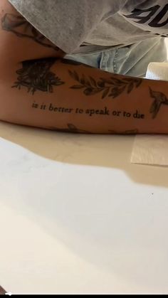 a man with tattoos on his arm sitting at a table