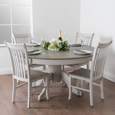 a dining room table with four chairs and a wine bottle on the top of it