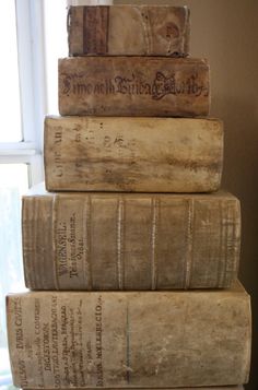 a stack of old books sitting on top of each other in front of a window