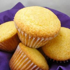 three yellow muffins sitting on top of a purple cloth next to each other