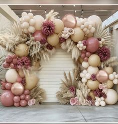 a bunch of balloons that are in the shape of a wreath on a wall with palm leaves and flowers