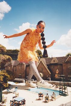 a woman in yellow dress standing on top of a pool