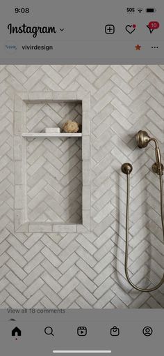 the bathroom is decorated in white herringbone tile and features a shower head, hand held showerhead, and built in shelving