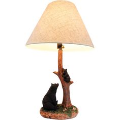 two cats sitting on a tree branch under a lamp