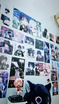 a wall covered in anime pictures and figurines next to a stuffed animal toy