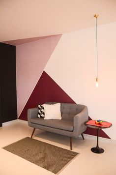 a living room with a gray couch and red accent wall in the corner next to a small table