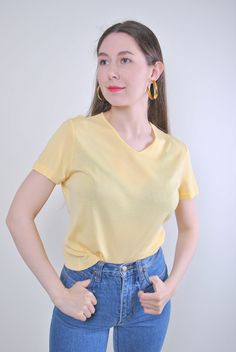 Indulge in the retro charm of our 90s Yellow Pullover Top, a vintage gem from TARASCOMMON.ETSY.COM's collection of unique clothing from the 20th century. Size: M Sleeve: 1.57 inches (armpit to end of sleeve) Width: 17.32 inches Length: 19.68 inches This vintage pullover features a minimalist design with a flattering v-neck, perfect for adding a pop of color to your wardrobe. Whether you're aiming for a retro look or a casual ensemble, this top is versatile and timeless. Crafted from comfortable Retro V-neck T-shirt For Spring, Vintage V-neck T-shirt For Spring, Vintage Cotton V-neck Top, Retro Cotton V-neck Tops, Vintage Cotton V-neck T-shirt, Yellow Minimalist, Retro Yellow, Retro Minimalist, Vintage Pullover