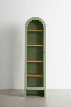 a green bookcase sitting on top of a cement floor next to a white wall