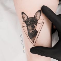 a person holding their arm with a small tattoo on it's thigh, showing the image of a dog