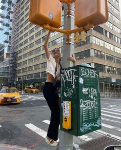 a woman standing on top of a pole next to a green box with some writing on it