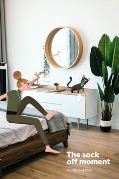 a person sitting on a bed in front of a mirror with a black cat standing next to it