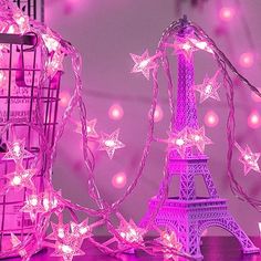 the eiffel tower is lit up with pink lights and stars on its side