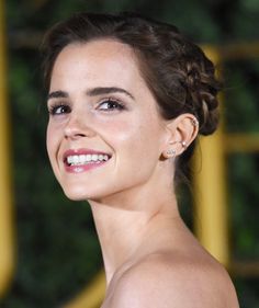 a woman in a strapless dress smiles at the camera while wearing diamond earrings