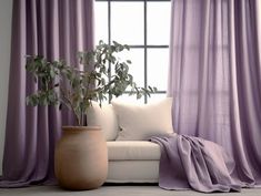 a white couch sitting next to a window covered in purple curtains and a potted plant