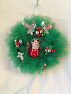 a christmas wreath hanging on the wall with ornaments around it and an ornament in the center