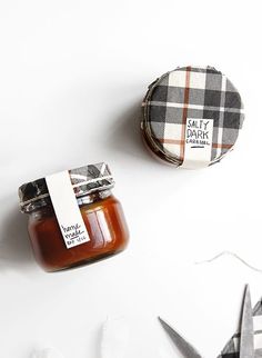 two jars of jam sitting on top of a table next to scissors and other items