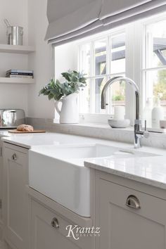 a kitchen with white cabinets and countertops has a window over the sink that is open to let in natural light