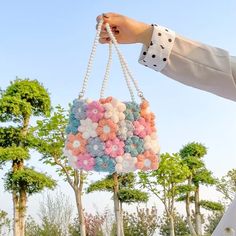 a person holding a bag with buttons on it in the grass and trees behind them