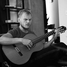 a man sitting in a chair playing an acoustic guitar